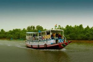 A boat cruising through the calm waters of the Sundarbans, surrounded by lush greenery, with an Indian flag visible on the boat's mast. The serene landscape highlights the beauty of the region.